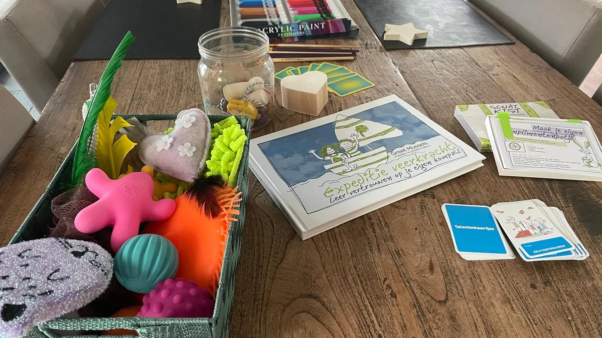Tafel met creatief materiaal voor de workshop: verf, gevoelsdoosje, talentenkaartjes en het boek Expeditie veerkracht